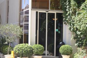a glass entrance to a building with potted plants at 2 KITARRAT Boutique Hotel & SPA in Durrës