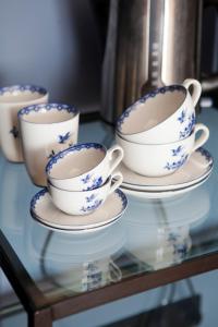 cuatro tazas y platillos azules y blancos sobre una mesa de cristal en suite no 7 en Ámsterdam