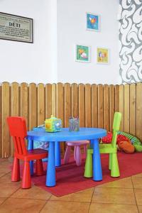 een blauwe tafel met vier kleurrijke stoelen eromheen bij Penzion U Kostela in Újezd