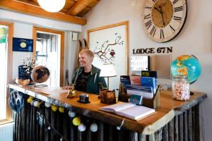 une femme assise à un bureau avec une horloge sur le mur dans l'établissement Lodge 67°N Lapland, à Äkäslompolo