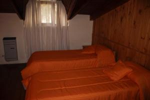 2 camas con sábanas de color naranja en una habitación con ventana en KALENA 4 Playa Bonita DAT en San Carlos de Bariloche