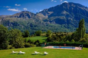 a group of chairs and a pool with mountains in the background at Piedrafita Mountain in Piedrafita de Jaca