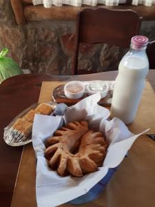 una mesa con un plato de bollería y una botella de leche en Aldea Serrana en Nono