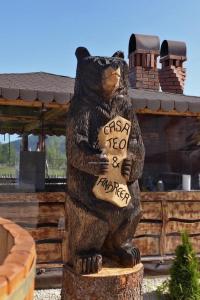 une statue d'un ours tenant un signe dans ses pattes dans l'établissement Casa Teo&Andreea, à Vatra Dornei
