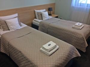 two beds in a hotel room with towels on them at 3Rooms in Kraków