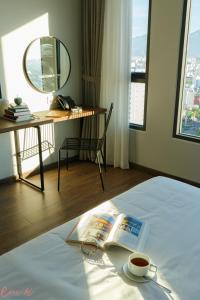 a hotel room with a bed with a book and a cup of coffee at Em Oi Boutique Hotel in Nha Trang