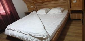 1 cama con sábanas blancas y almohadas en una habitación en Bujtinat e lugines Valbone, en Valbonë