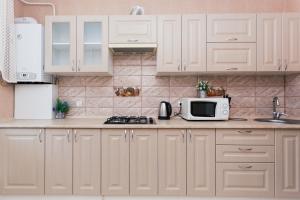a kitchen with white cabinets and a microwave at Luxury apart-hotel on Kharkovskaya New Building 6 floor in Sumy