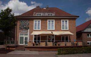 - un grand bâtiment en briques avec une terrasse couverte et un auvent dans l'établissement Altes Amtshaus, à Reken
