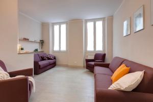 - un salon avec deux canapés violets et des fenêtres dans l'établissement Mamo Florence - Opera - Sinfonia - Minuetto - Melody Apartments, à Florence