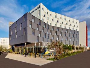 un grand bâtiment avec des tables et des chaises devant lui dans l'établissement Golden Tulip Bordeaux Euratlantique, à Bordeaux