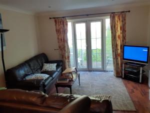 a living room with a leather couch and a flat screen tv at Double Room in Honiton House in Hendon