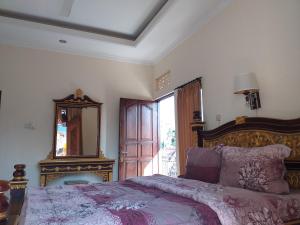 1 dormitorio con 1 cama grande y espejo en Puri Asri Bungalow Ubud en Ubud