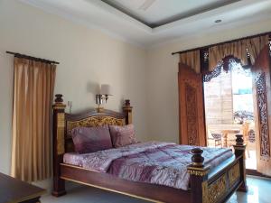 Un dormitorio con una cama con marco de madera. en Puri Asri Bungalow Ubud, en Ubud