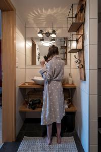 a woman standing in front of a sink in a bathroom at Privatzimmer Haring in Kitzeck im Sausal
