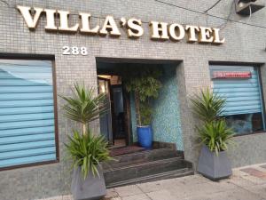 um hotel com dois vasos de plantas em frente a um edifício em Villas Hotel em São Paulo