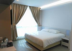 a bedroom with a white bed and a large window at Legacy Hotel Ipoh in Ipoh