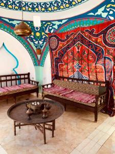 a room with two benches and a table with a colorful wall at Cleopatra Hotel Luxor in Luxor
