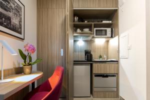 a small kitchen with a counter and a red chair at Nemea Appart Hotel So Cloud Lyon Gare Part-Dieu in Lyon