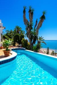 a swimming pool with palm trees and the beach at Stunning Beachclose Villa by Costarentals - Ref 03 in Fuengirola