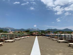 a row of benches on a beach with mountains in the background at Exclusive Loft 300mt by the sea Forte dei Marmi in Forte dei Marmi