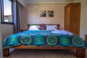 a bed with a blue and green blanket on it at Ossanzaia Bilene Lodge in Vila Praia Do Bilene