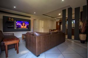 sala de estar con sofá y TV en la pared en Ossanzaia Bilene Lodge, en Vila Praia Do Bilene