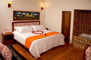 a bedroom with a large bed with an orange blanket at Hotel Villa Alegria in Sáchica