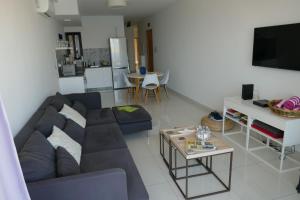 Una sala de estar con un sofá azul y una mesa. en Calypso Court, en Mellieħa