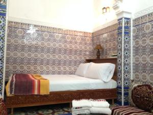 una camera da letto con un letto e pareti piastrellate in blu e bianco di Riad Soul of Tetouan a Tétouan