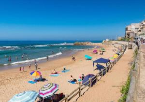 people on a beach with umbrellas and the ocean at Escape to a Seaside Sanctuary - vayKZN Umdloti in Umdloti