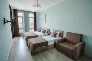 una habitación de hotel con 2 camas y una silla en Hotel Holiday Villa en Tiflis