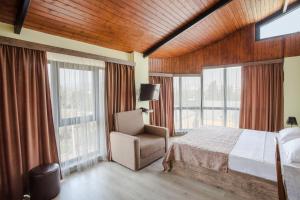 a bedroom with a bed and a chair and windows at Hotel Holiday Villa in Tbilisi City