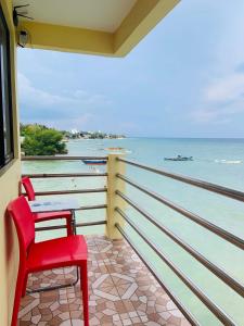 a red chair sitting on a balcony looking out at the ocean at Sascha's Resort Oslob in Oslob