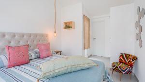 Schlafzimmer mit einem Bett mit rosa und blauen Kissen in der Unterkunft Vila Varanda by Sevencollection in Salema