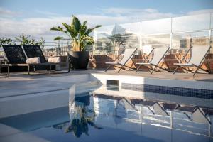 eine Terrasse mit Stühlen und einen Pool auf einem Gebäude in der Unterkunft Silken Ramblas in Barcelona