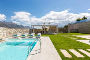 una piscina con sillas y una casa en Thalmargia Villas, Ultimate Peace & Privacy, By ThinkVilla en Rethymno Town