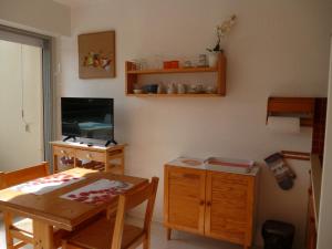 a living room with a table and a television at Studio LUMINEUX avec belle TERRASSE sur ESPACES VERTS, 100m PLAGE in Carnac-Plage
