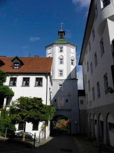 um edifício branco com uma torre de relógio ao lado de dois edifícios em FeWo Zum Kuhturm em Günzburg