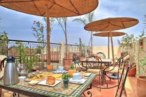 einen Tisch mit Essen auf einer Terrasse mit Sonnenschirmen in der Unterkunft Dar Al Hamra in Marrakesch