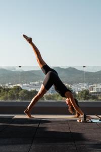 a woman doing a yoga pose on a yoga mat at OKU Ibiza in San Antonio