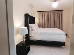 a bedroom with a white bed and a lamp at Embassy Gardens 17 West Rd South Morningside Sandton Johannesburg Secure 2 Bedroom fully furnished apartment with 24hrs security in Johannesburg +6 photos