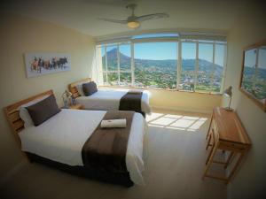 two beds in a room with a large window at Disa Park 17th Floor Apartment with City Views in Cape Town