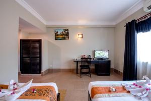 a room with two beds and a desk and a television at Central Night Hotel in Siem Reap