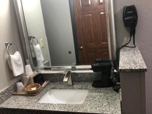 a bathroom with a sink and a large mirror at Texas Inn and Suites Lufkin in Lufkin