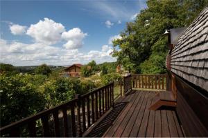 una terraza de madera con un banco en el lateral de una casa en Le Chalet du Chemin et sa Roulotte, en Berviller-en-Moselle