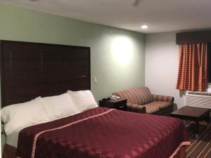 a hotel room with a bed and a chair at Texas Inn and Suites Lufkin in Lufkin