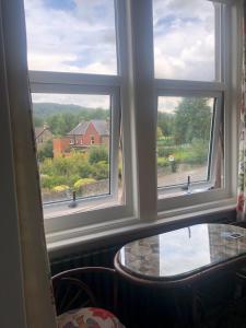 a room with three windows and a glass table at Avenue House in Bakewell