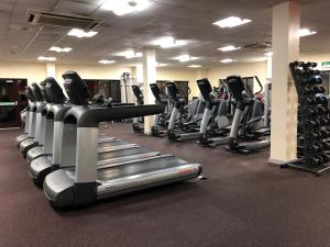 a gym with a row of treadmills and machines at National Badminton Centre Lodge & Health Club in Milton Keynes