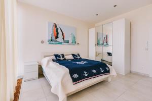 um quarto branco com uma cama com um cobertor azul em Villa Georgina em Badacsonytomaj